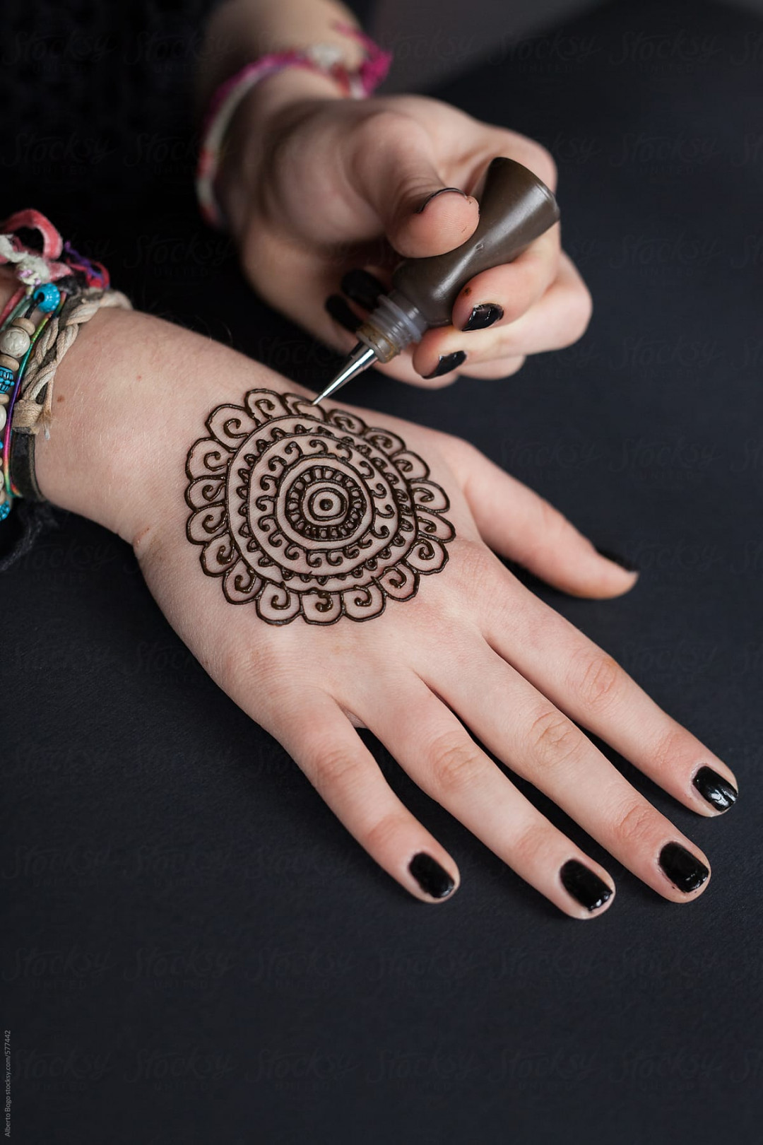 Woman Drawing A Henna Tattoo On A Hand" by Stocksy Contributor